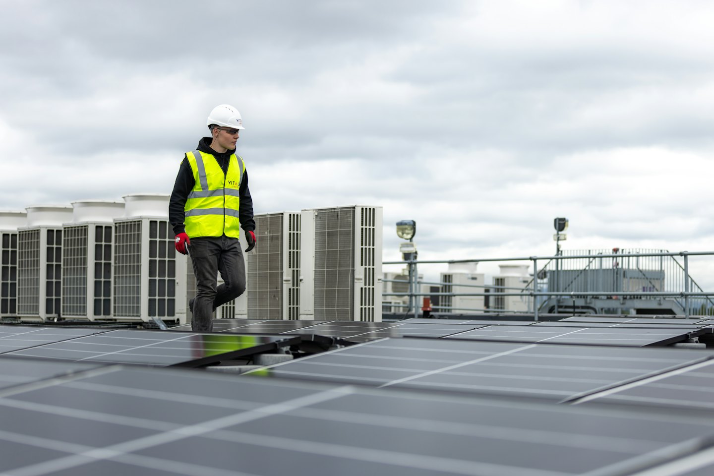 Technik sprawdza panele słoneczne i jednostki HVAC na dachu komercyjnym.